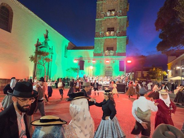 Baile de magos en La Laguna frente a una iglesia iluminada, con músicos y bailarines vestidos con indumentaria tradicional canaria.