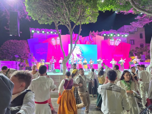 Actuación folclórica en Gran Canaria con músicos sobre el escenario y parejas bailando con trajes tradicionales canarios.