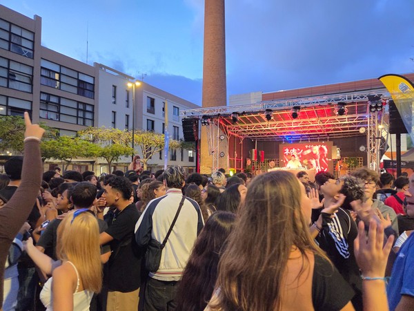 Festival de música electrónica en La Laguna con un DJ actuando ante una multitud de jóvenes al aire libre.
