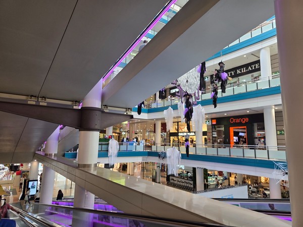 Decoración de Halloween en el centro comercial Añaza con fantasmas colgantes, telarañas y tiendas en varios niveles.
