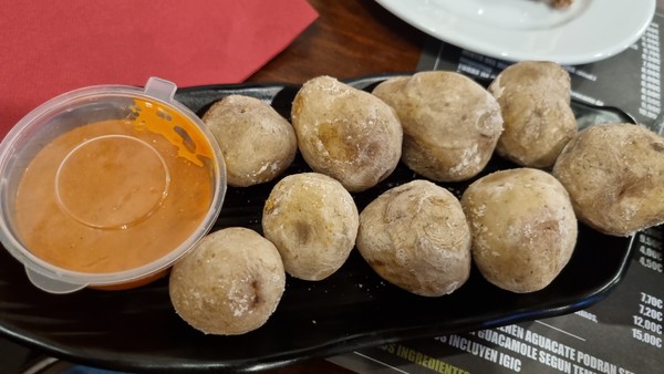 Plato de papas arrugadas canarias servidas con salsa mojo roja en un restaurante.