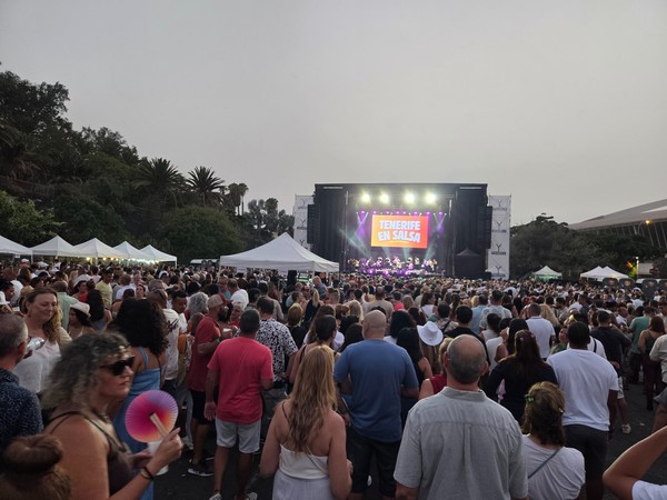 Festival de salsa en Tenerife con un gran escenario iluminado y una multitud de personas reunidas al aire libre frente al concierto.